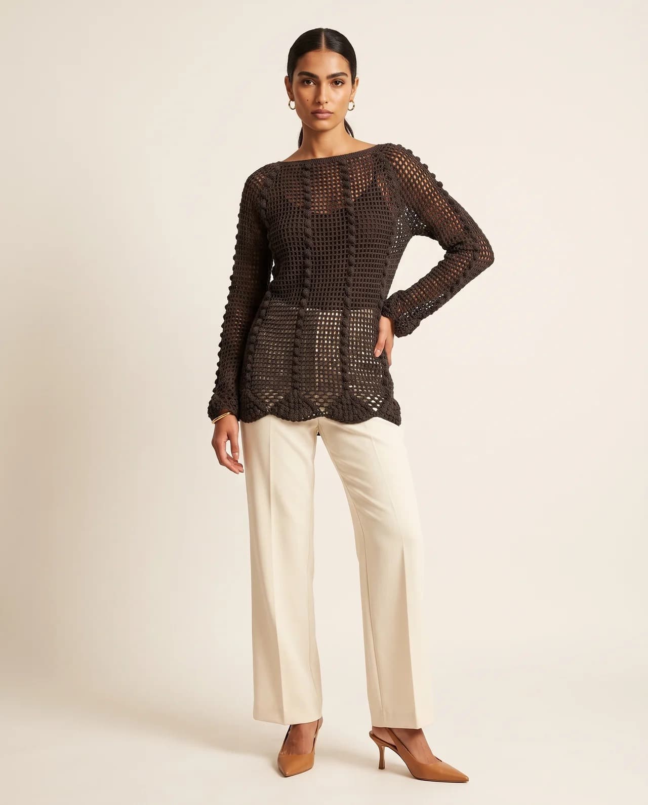 Model in a long-sleeved chocolate open-work crochet blouse with cream trousers