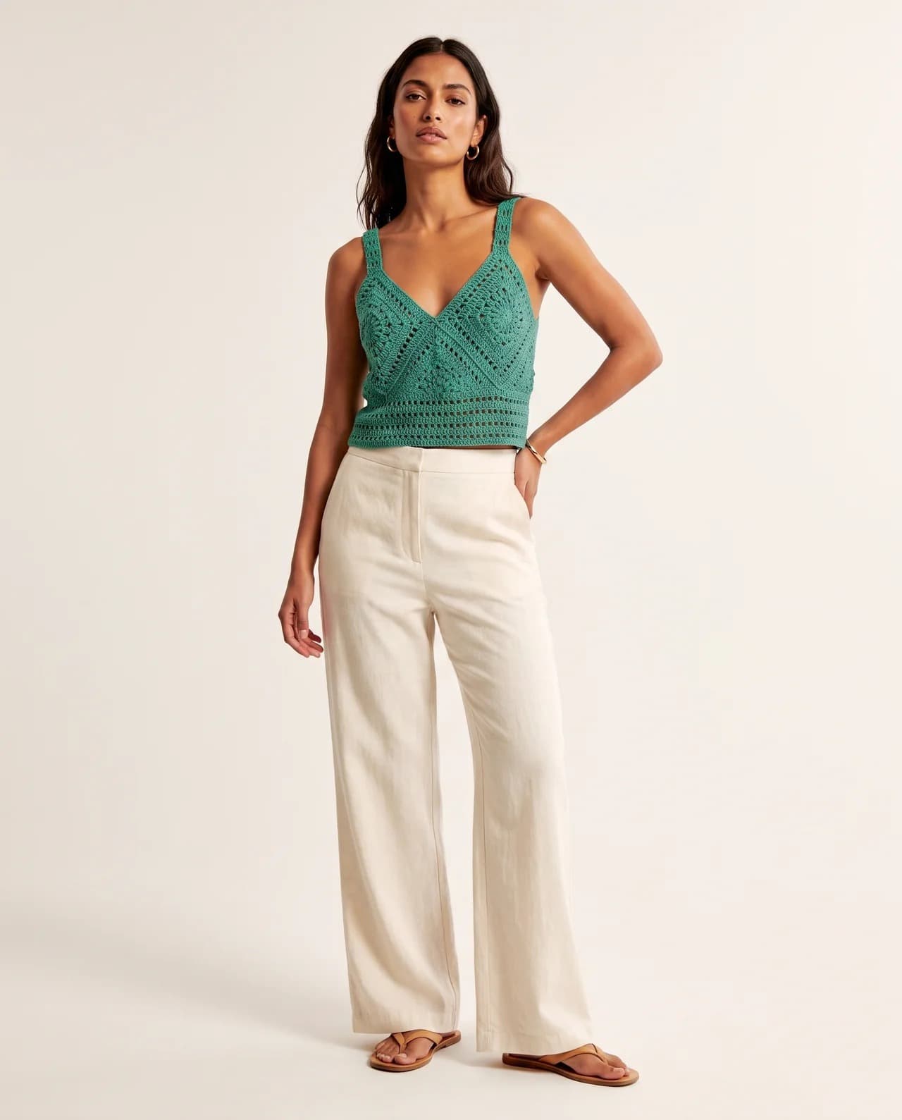 Model in a green crochet bralette with cream wide-leg trousers