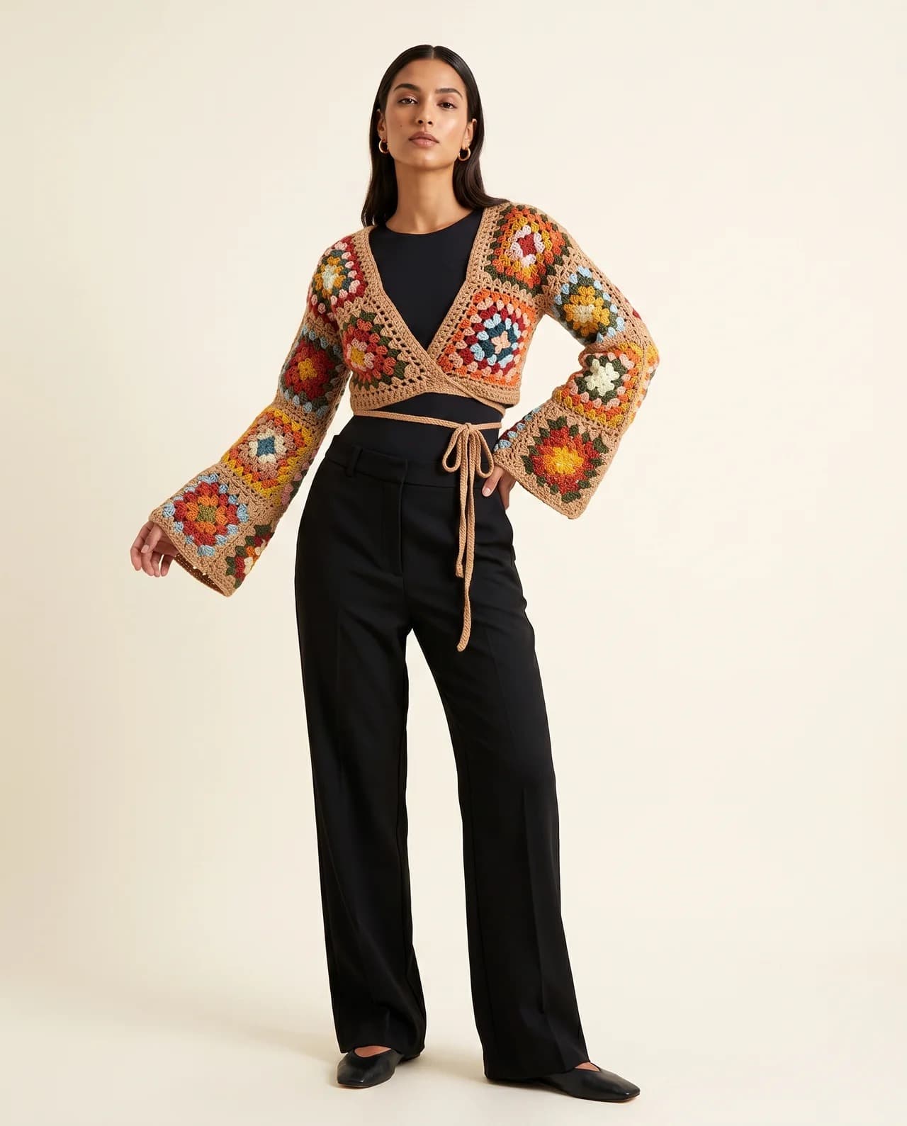 Model in a cropped multicolour granny-square crochet bolero tied at the waist, over black trousers