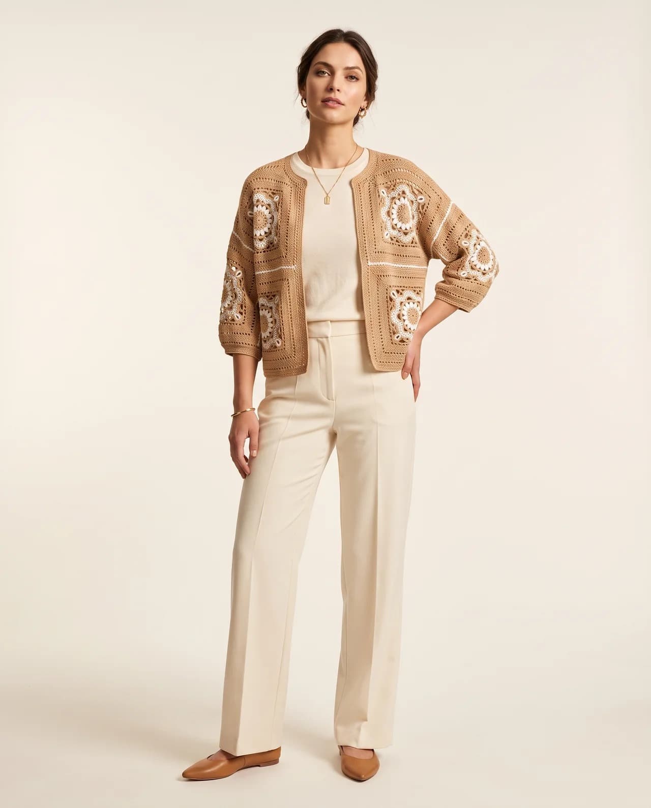 Model in a camel granny-square crochet cardigan with cream floral motifs, worn over cream trousers