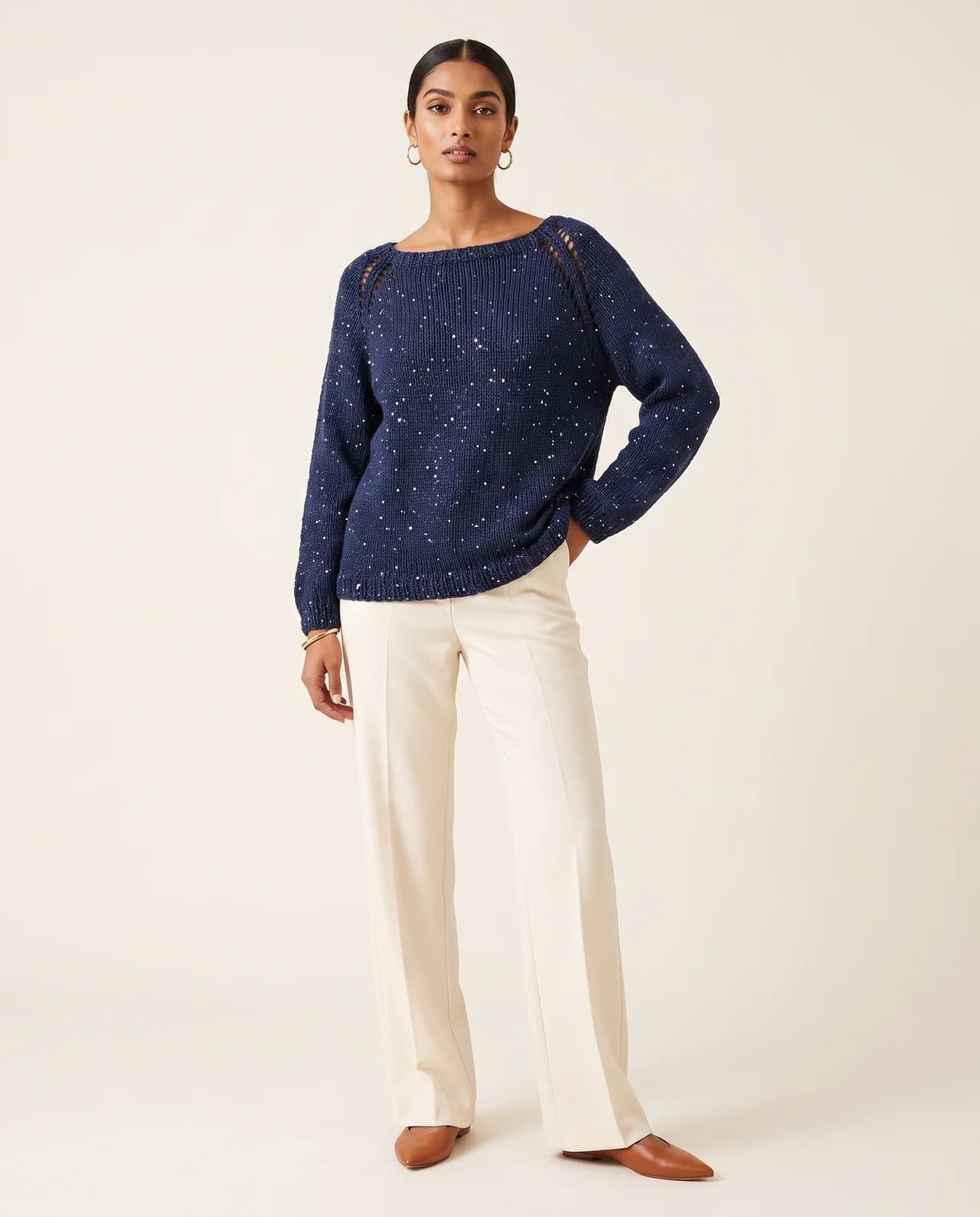 Model in a navy hand-knit sweater with cream trousers