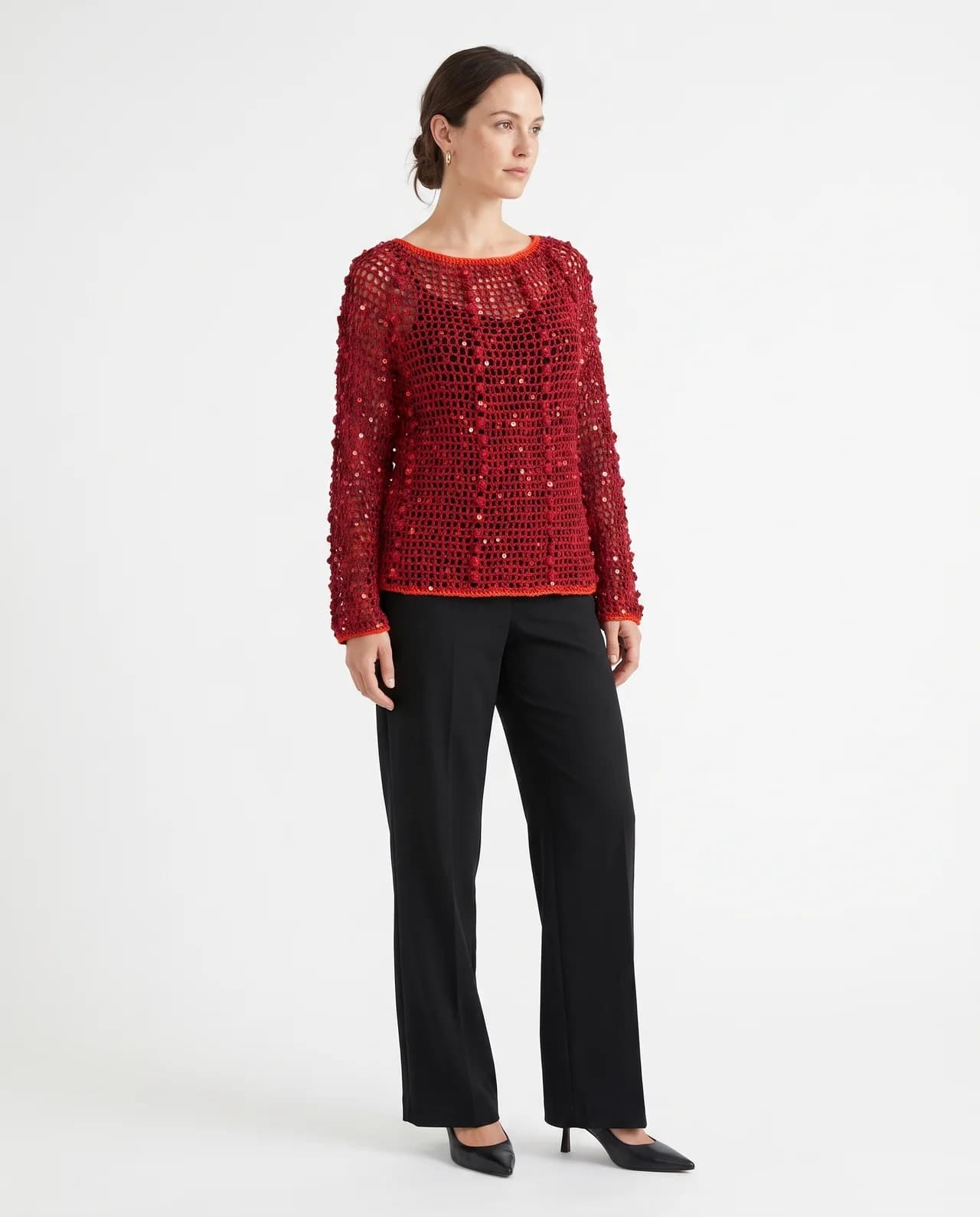 Model in a deep red hand-crocheted blouse with scattered sequins, worn with black trousers