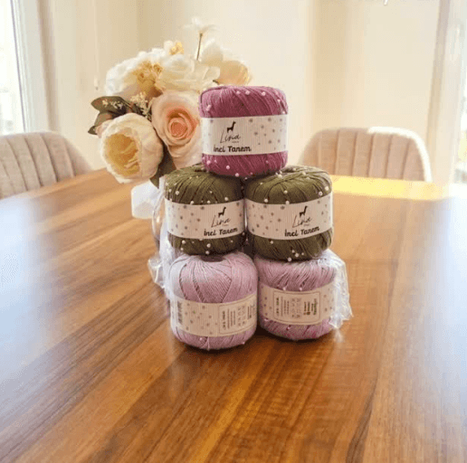Yarn cones stacked beside flowers on a wooden table